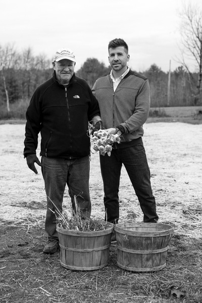 Bill and Max Higgins stand with bunches of garlic bulbs at their Homestead View Farm in the town of Northumberland. The father-and-son team produce their own line of Saratoga Garlic sauces. Joan K. Lentini photo